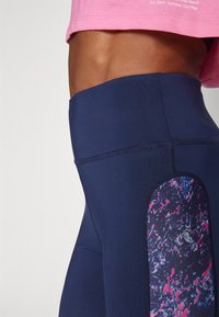 Navy leggings with a colorful, abstract pattern on the side panel. Smooth fabric with flat seams for comfort and a high waistband design.