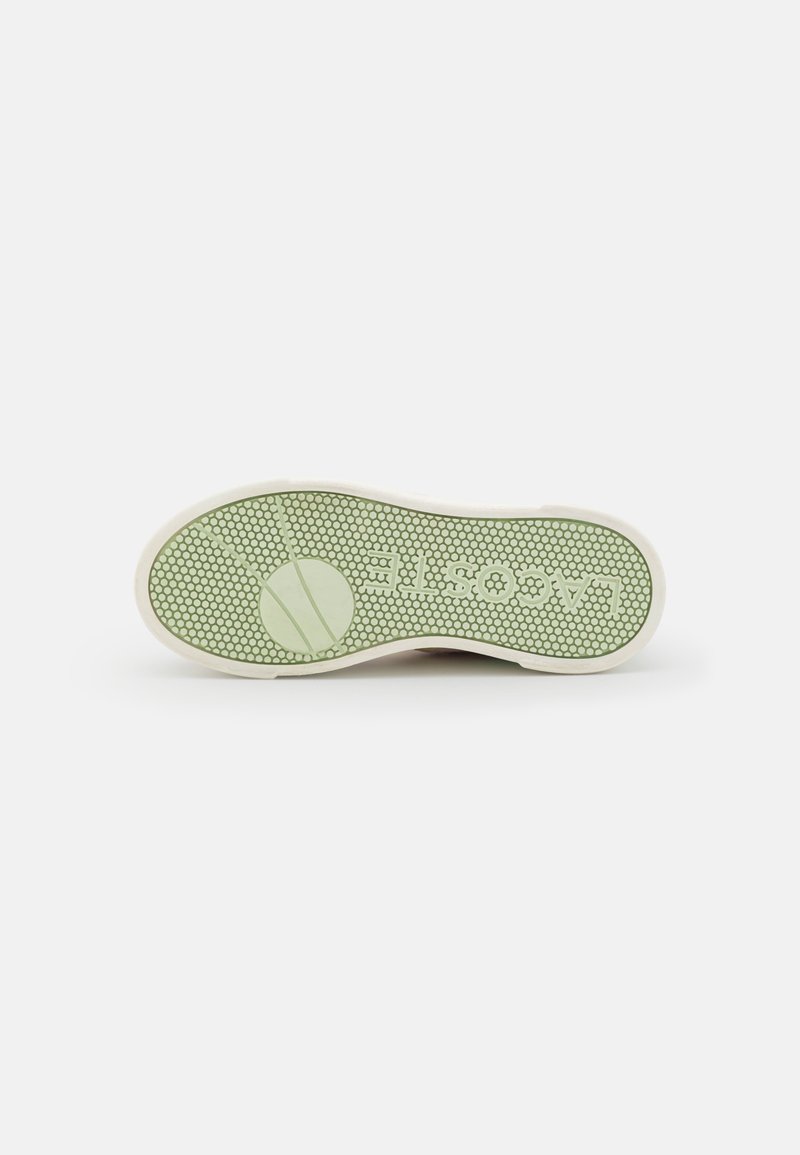 Sneakersohle mit einer hellgrünen Gummiäußenschicht und einem Wabenmuster. Der Text "lacoste" ist eingeprägt, und in der Mitte befindet sich ein kreisförmiges Design.
