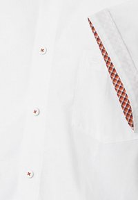 Weißes Button-up-Hemd mit roten Knöpfen, das ein karierter Innenfutter aus Orange und Blau an der Manschette und am Taschenrand aufweist.