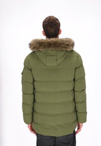 Olivengrøn polstret jakke med en hætte med pelskant, der har syninger i vandrette sektioner, sidelommer og en buet kant.