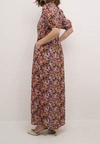 Robe maxi fleurie présentant une variété de fleurs roses, violettes et orange sur un fond noir, avec des manches courtes bouffantes et des poches latérales.