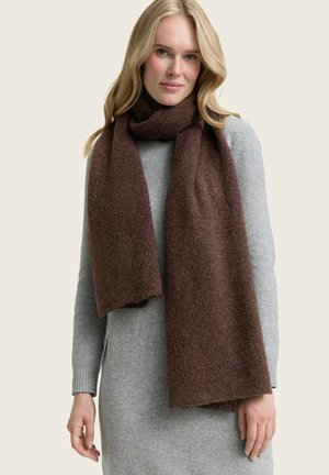 Brown knitted scarf made of textured fabric, draping around the neck. Worn with a gray sweater, featuring a ribbed cuff.