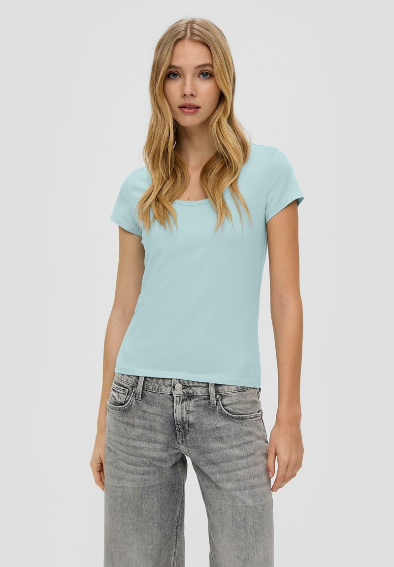 Helles blaues, tailliertes T-Shirt mit Quadrat-Ausschnitt, kurzen Ärmeln und glatter Textur, kombiniert mit grauen Jeans im used Look.