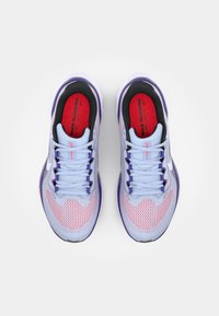 Des chaussures de course en bleu clair et violet, dotées d'une tige en maille, d'un bout arrondi, d'accents rouges et d'un col rembourré noir avec une marque visible.