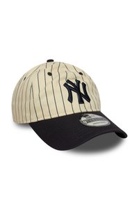 Beige baseballcap med marineblå striper, med en mørk marineblå visir og brodert logo. Justerbar stropp bak.