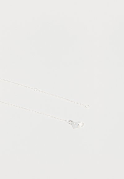 Collier fin en chaîne argentée avec un petit pendentif carré et un fermoir en forme de homard sur un fond uni clair.