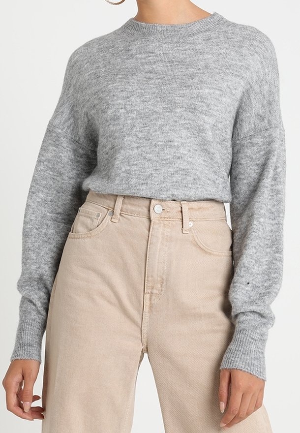 Ljusgrå stickad tröja med ribbat rundhals och lösa ärmar, kombinerad med högmidjade beige manchesterbyxor.