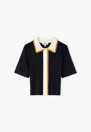 Cárdigan negro de manga corta con panel frontal de botones blancos, cuello de crochet blanco bordeado con ondas en amarillo mostaza y ribete en amarillo mostaza.