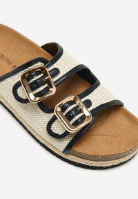 Beige og marineblå slidesandal med to justerbare stropper featuring guld-spænder, tekstureret stofoverdel og en sål i naturlig farve.