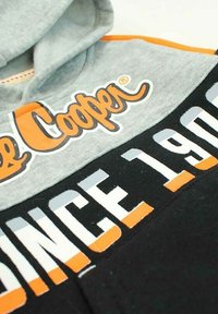 Sweat à capuche avec une partie supérieure grise et une partie inférieure noire. Présente le logo "Cooper" en orange et "SINCE 1900" en blanc et gris. Texture de tissu douce.