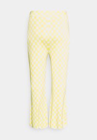 Calças amarelas cropped com um padrão de corações brancos. O tecido tem uma textura suave, com um design ajustado e bainha evasê.