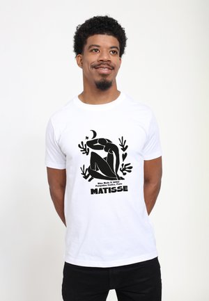 Bílý bavlněný tričko s černou grafickou potiskem posezené postavy, obklopené rostlinnými motivy, a textem "MATISSE" dole.