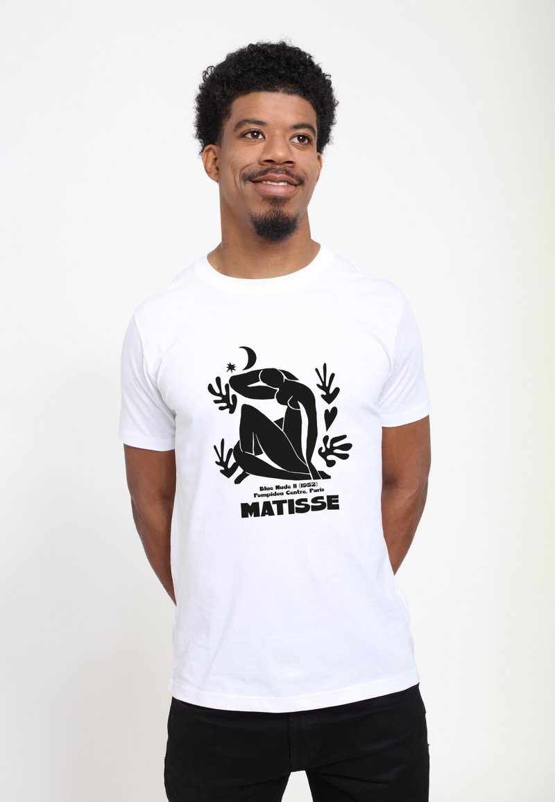 Hvid bomulds t-shirt med en sort grafisk tryk af en siddende figur, omgivet af plante-motiver, og teksten "MATISSE" nedenfor.
