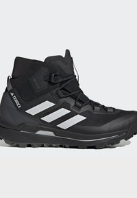 Sort højtop Adidas Terrex vandrestøvle med tre hvide striber, Gore-Tex label og robust sål til udendørs brug.