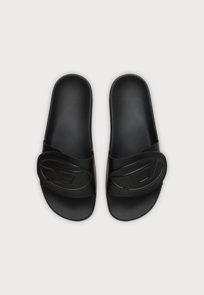Paire de sandales noires à enfiler avec semelles texturées et larges brides réglables sur fond gris.