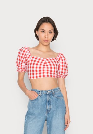 Top cropped em padrão vichy vermelho e branco, com mangas bufantes, decote quadrado e cintura justa, combinado com jeans de ganga azul de cintura alta.