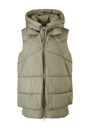 Person iført en lysegrøn quiltet dunjakke med et sort ribbet tøj synligt under.