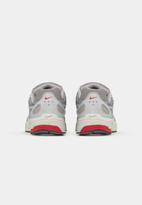 Graue Sportschuhe mit Obermaterial aus Mesh, roten Akzenten und einer weißen Mittelsohle. Verfügt über eine abgerundete Ferse und auffällige Markierung auf der Rückseite.