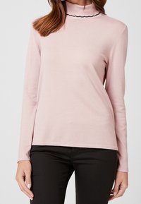 Helles rosa Langarmoberteil mit hohem Kragen und schwarzem gewelltem Saum. Hergestellt aus weichem Stoff mit einer figurbetonten Passform.