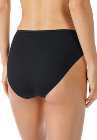 Svarta högmidjade underkläder tillverkade av elastisk tyg, med en smidig finish och minimala sömmar för en sömlös look.