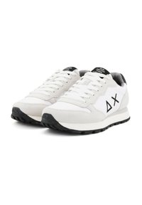 Weiße Sportschuhe aus Wildleder und Mesh, mit einer schwarzen Sohle, weißen Schnürsenkeln und einem markanten schwarzen Logo an der Seite.