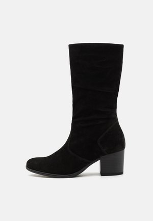 Botte pour femme en daim noir montant jusqu'au milieu du mollet, avec talon bloc et pointe légèrement arrondie, vue de profil sur un fond clair uni.