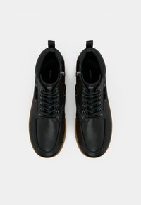 Czarne skórzane buty za kostkę o gładkim wykończeniu, z szarymi sznurówkami, metalowymi oczkami i gumową podeszwą. Zaprojektowane z wsparciem dla kostki.