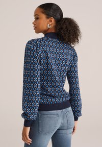 Maglione a maglia blu navy con motivo a diamante in diverse tonalità di blu e bianco, con polsini e orlo a costine.