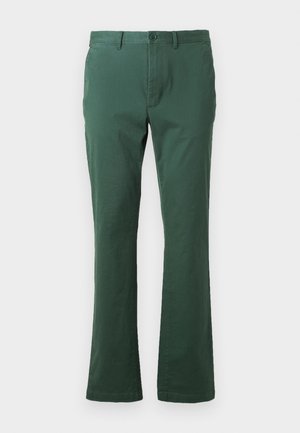 Vihreät pellavahousut, joissa on sileä rakenne, suora lahjemuotoilu ja napin kiinnitys vyötäröllä. Sisältää etutaskut ja siistin viimeistelyn.