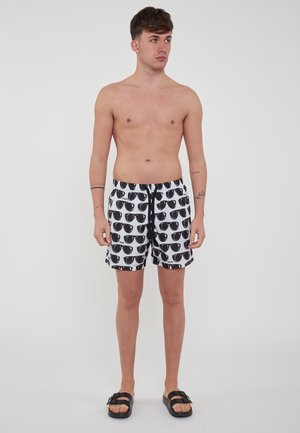 Pantaloni da bagno da uomo con sfondo bianco e motivo di occhiali da sole neri, caratterizzati da una vita elastica e lacci. Tessuto testurizzato.