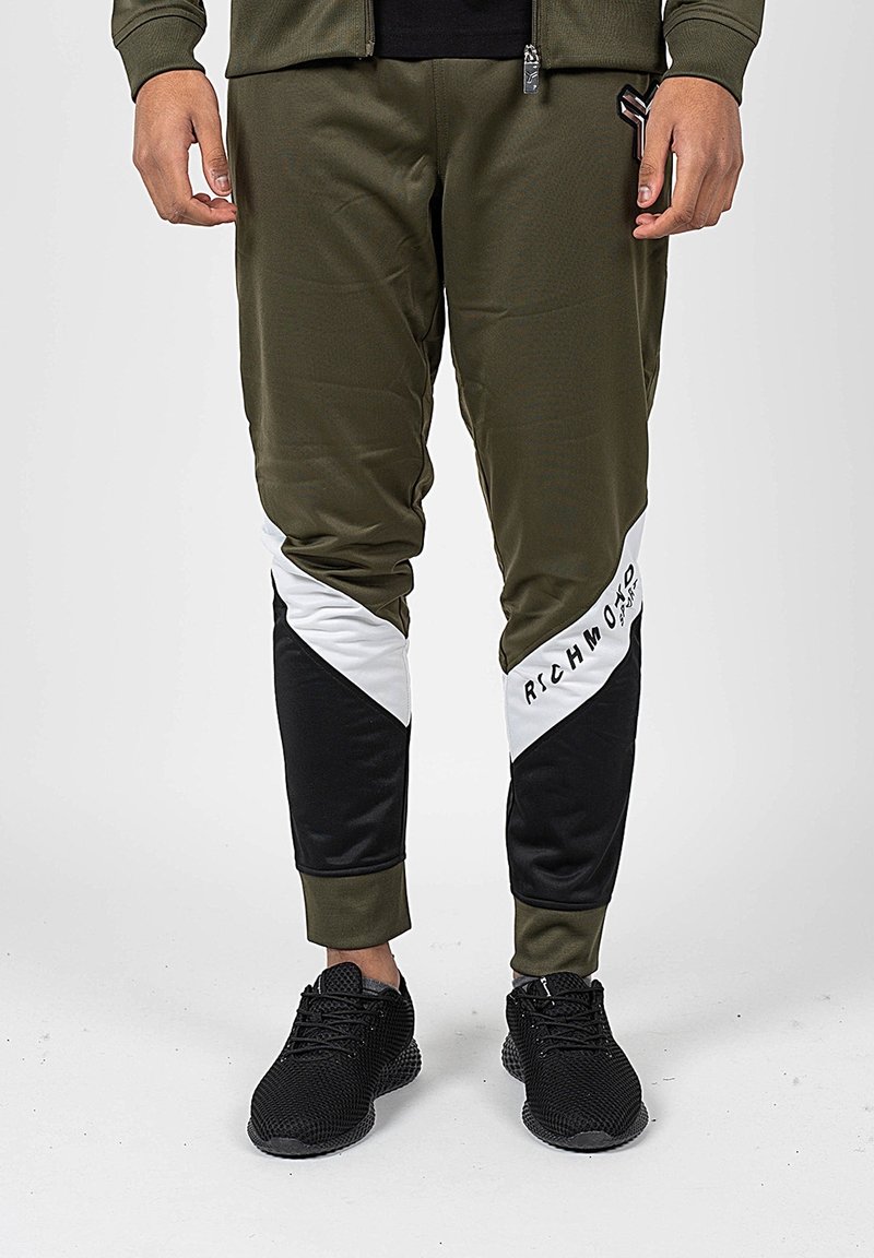 Atletické tepláky v olivově zelené barvě s černobílými diagonálními akcenty; mají přiléhavý design a elastické manžety.