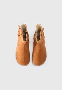 Bottines en daim marron avec un bout arrondi, des fermetures éclair sur les côtés et des accents frangés au niveau du talon. Surface texturée et semelle en caoutchouc.