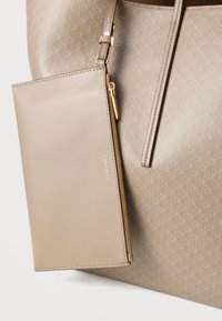 Μπεζ δερμάτινη τσάντα ώμου με υφασμάτινο σχέδιο και αφαιρούμενο πορτοφόλι σε ταιριαστό χρώμα, με χρυστό φερμουάρ και διακοσμητικά με λογότυπο.