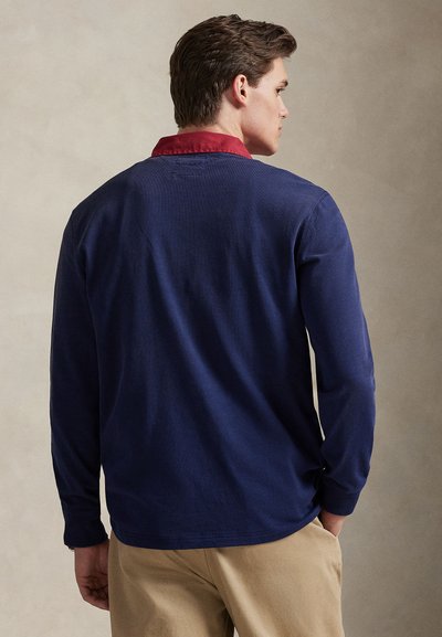 Μακρυμάνικο πουκάμισο σε ναυτικό μπλε με κόκκινο γιακά. Υφασμένο ύφασμα με υφή, απλός σχεδιασμός και άνετη εφαρμογή. Φαίνεται από πίσω, με λεπτομερείς ραφές.