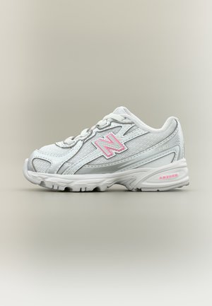 Λευκό αθλητικό παπούτσι New Balance με ροζ λογότυπο και αποσβεστική σόλα, εμφανιζόμενο από το πλάι σε ουδέτερο φόντο.