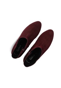 Een paar donkerrode suède enkellaarzen met een zijrits en zwarte binnenzolen, gemarkeerd met "Gabor", op een witte achtergrond.