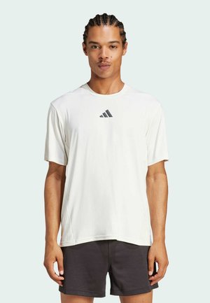 T-shirt de sport blanc à manches courtes, au col rond et à la texture subtile, avec un logo foncé sur la poitrine et une coupe ample.