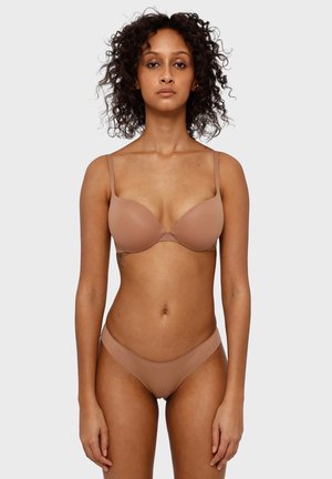 Světle nahá push-up podprsenka s hladkými košíčky a nastavitelnými ramínky. Odpovídající bikiny s minimálním pokrytím. Jemná, bezešvá textura po celém výrobku.