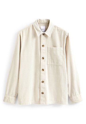 Chemise en velours côtelé beige à manches longues, avec un devant boutonné et une poche poitrine unique. Elle présente des côtes verticales et des boutons en bois.