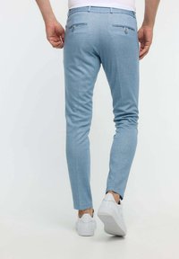 Hellblaue, schlank geschnittene Hosen mit zwei Gesäßtaschen und glatter Textur, kombiniert mit weißen Sneakern.