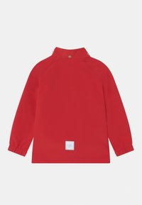 Pullover rouge à manches longues avec un col haut, des poignets élastiques et une étiquette de logo blanche en bas. Texture lisse avec une coupe ajustée.