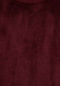 Tissu rouge foncé texturé avec une surface douce et duveteuse et un col côtelé légèrement visible en haut.
