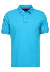 Jasnoniebieski polo wykonany z bawełny, z klasycznym kołnierzykiem, zapięciem na dwa guziki i małym haftowanym logotypem na piersi.