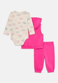 Tre-delt barneklær: kremfarget bodysuit med sløyfe-mønster, rosa quiltet ermeløs hettejakke og rosa joggebukser med elastiske mansjetter.