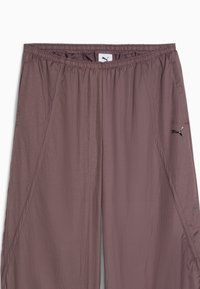 Lettere, mauve atletiske bukser med elastisk talje, glat tekstur og et lille sort logo på venstre side.