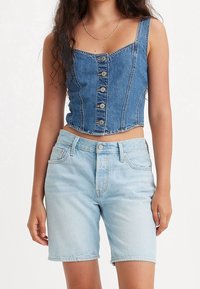 Jeanscrop top med fyrkantig halsringning, med framknappar och synlig sömnad. Matchas med ljusblå, högmidjade jeansshorts.