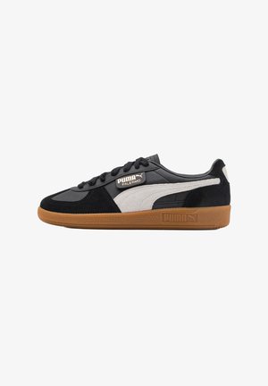 Black and grey sneaker featuring a suede and leather upper, lace closure, and a brown rubber sole with PUMA branding.