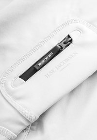 Biała tkanina o gładkiej strukturze posiada boczny zamek błyskawiczny oraz metkę z napisem "ILSE JACOBSEN HORNBÆK". Szwy są starannie wykonane i wzmocnione.