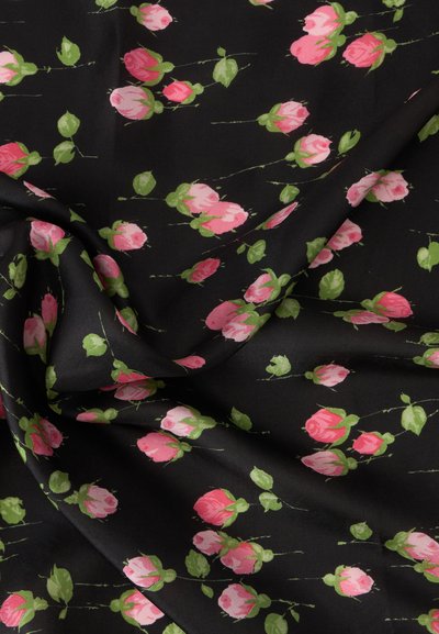 Tissu noir avec de petits boutons de rose roses dispersés et des feuilles vertes, montrant des plis et la texture.