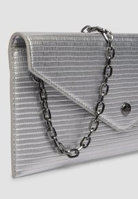 Srebrna kopertówka o teksturowanym wykończeniu. Posiada złożony design, czarny łańcuszek oraz zapięcie na zatrzask.
